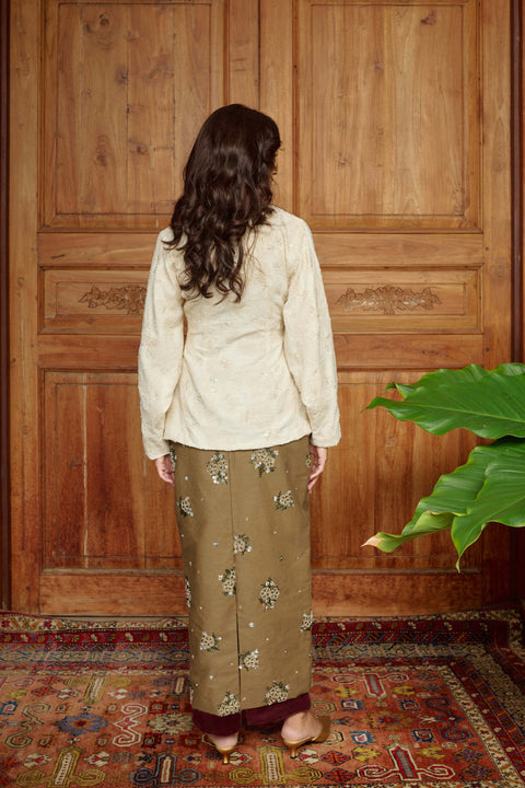 Person wearing a cream blouse and patterned skirts