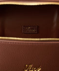 Close-up of a brown leather bag with gold stitching and 'Saoi' branding.