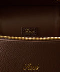 Close-up of a brown leather bag with gold zipper and visible brand logo.