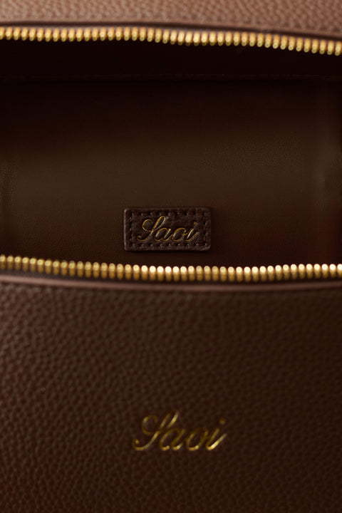 Close-up of a brown leather bag with gold zipper and visible brand logo.