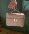 Pink jewelry bag with gold accents held by a hand as a clutch